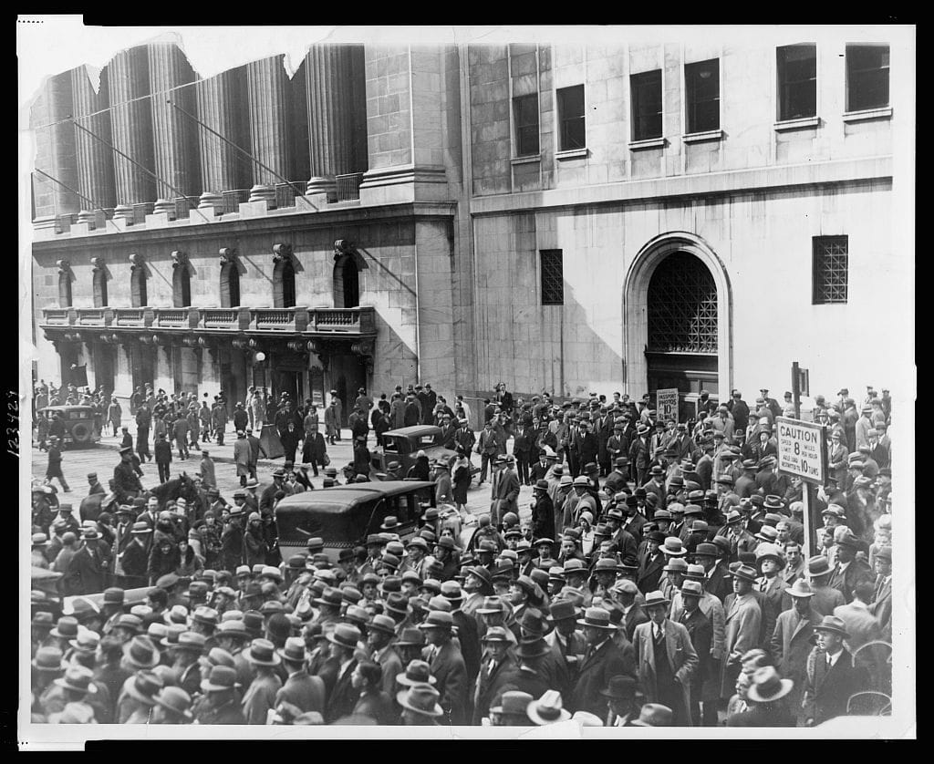 A large crowd of men in hats and overcoats fills Wall Street outside the New York Stock Exchange during the crash of October 1929.
